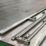 A product inspection station or quality control point, showing an operator or automated sensor checking the dimensions, finish, and integrity of the newly formed solar panel mounting frame components.