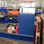 Eine robuste industrielle hydraulische Abwickelvorrichtung hält eine große Stahlcoil, die den Ausgangspunkt des Walzformprozesses markiert.