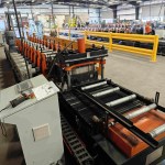 Ein fliegender Hydraulikschneider zerschneidet das fertige C-Verstrebungsprofil, während die Maschine mit hoher Geschwindigkeit läuft.