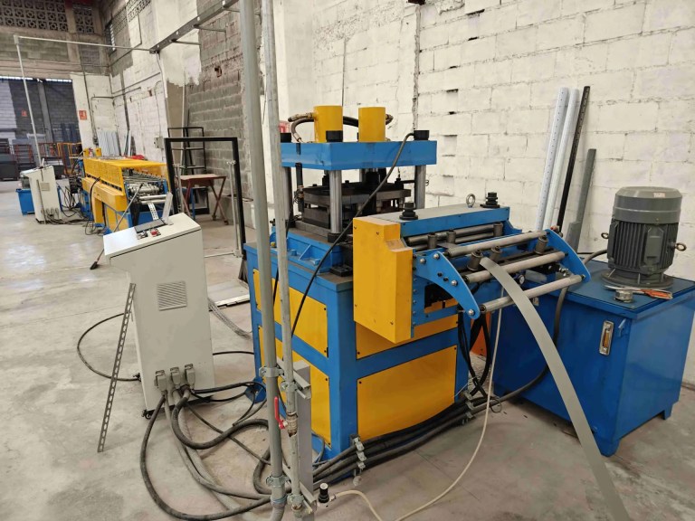 Nahaufnahme des Servo-Zuführers und der hydraulischen Stanzvorrichtung, die präzise Löcher in den Metallstreifen erzeugen.