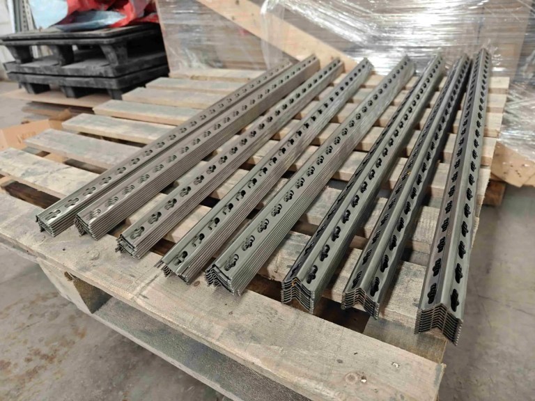 Stapel von präzisionsgeschnittenen, fertig bearbeiteten Metallregalpfosten, die das einheitliche Profil und die durchgehenden Stanzlöcher zeigen.
