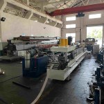 Gros plan sur le dispositif d'alimentation et de guidage du matériau de la profileuse, montrant la bande de métal dirigée avec précision vers les premiers rouleaux de la machine.