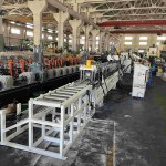 Vue d'ensemble de la machine de profilage de rails DIN complète, montrant l'intégralité de la ligne de production, du dérouleur à gauche à l'empileur automatique à droite, et mettant en évidence toutes les principales étapes du processus.